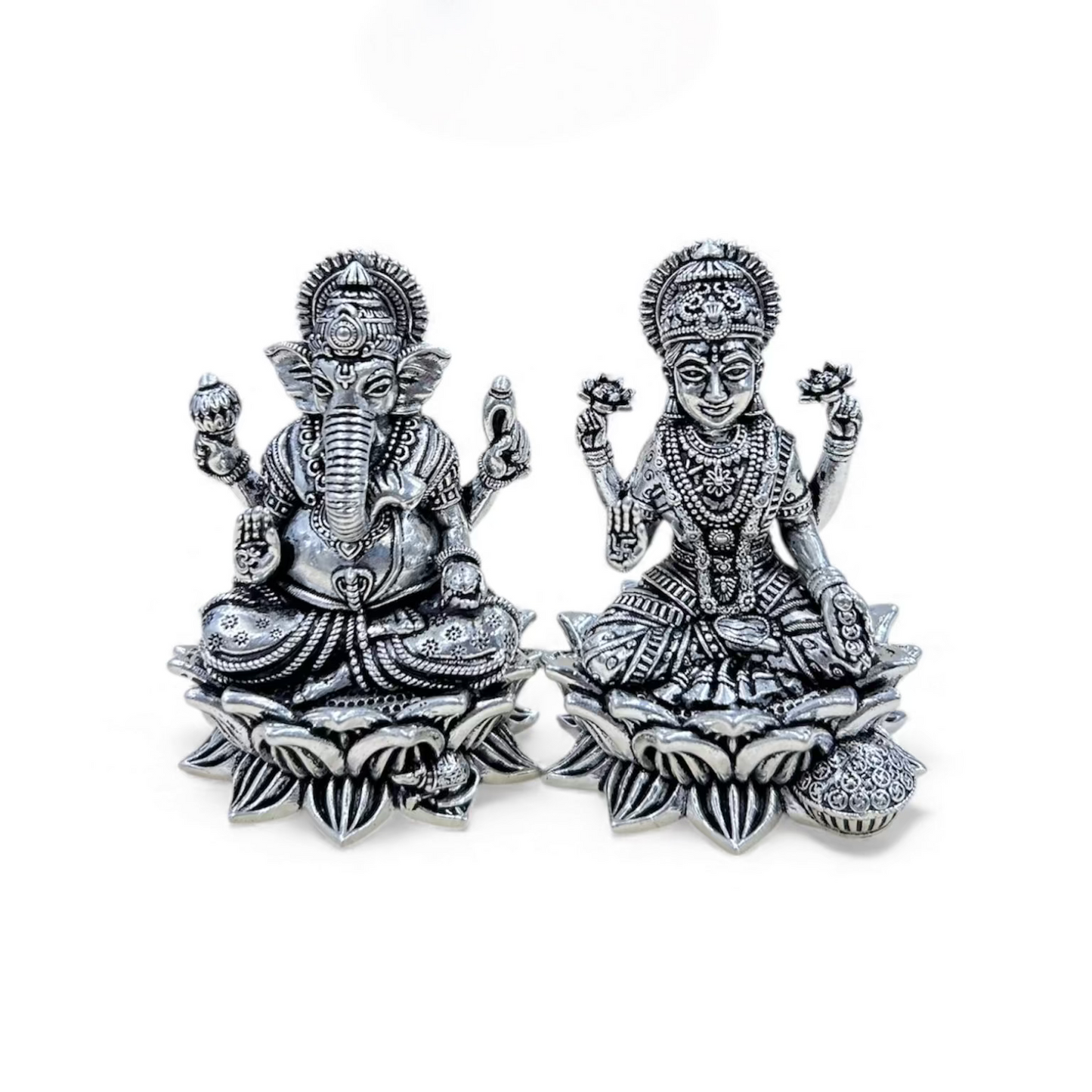 Silver statues of Ganesha and Lakshmi on a white background