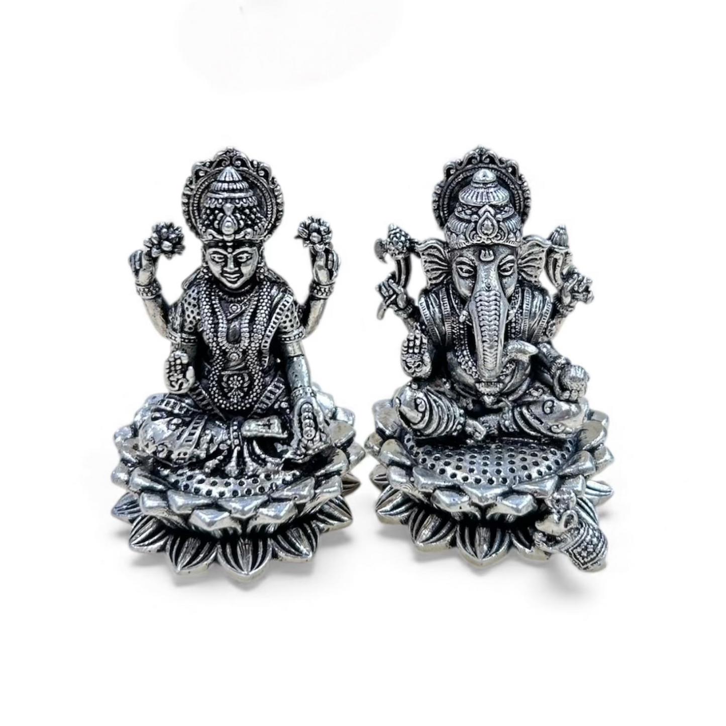 Pair of silver deity figurines on a white background